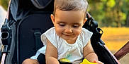 Seyana participe au concours pour gagner de l'argent avec cette photo : baby, child, stroller, toy, yellow, hair_ties, outdoor, nature, greenery, sunlight, happy, cute, infant, playing, sitting, feet, hands, casual_clothing, daytime, portrait