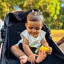baby, child, stroller, toy, yellow, hair_ties, outdoor, nature, greenery, sunlight, happy, cute, infant, playing, sitting, feet, hands, casual_clothing, daytime, portrait
