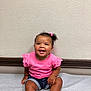 baby, bright, casual_clothing, child, cute, daylight, denim_shorts, hair_bow, happy, indoor, person, pink_shirt, portrait, sitting, skin, smile, toddler, wall, white_shoes, young_child