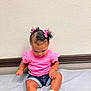 baby, casual_clothing, child, curious, curly_hair, cute, denim_shorts, floor, hair_bows, indoor, looking_down, pink_shirt, portrait, shorts, sitting, small_child, socks, toddler, wall, white_shoes