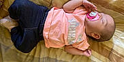 Lucia is registered to the contest to win money with this photo: baby, sleeping, pacifier, pink_shirt, dark_pants, blanket, infant, resting, cute, child, peaceful, indoors, soft_lighting, portrait, one_person, young_child, casual_clothing, head, hand, footwear