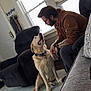 blinds, carpet, casual_clothing, chair, dog, door, glasses, home, indoor, interaction, labrador, light, man, pet, relaxation, sofa, tattoo, toy, watch, window