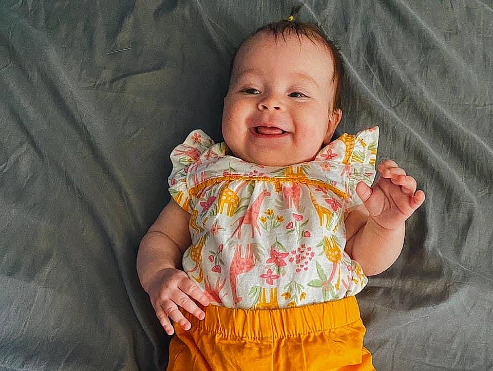 Leilani is registered to the contest to win money with this photo: baby_toddler_clothing, cheek, chin, clothing, eye, face, facial_expression, hand, happy, head, human_body, joy, nose, organ, outerwear, person, pink, skin, sleeve, smile