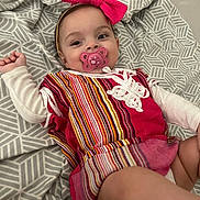 Mahira participe au concours pour gagner de l'argent avec cette photo : baby, bedspread, bow, child, cozy, cute, fabric, happy, headband, indoor, infant, lying_down, pacifier, pattern, person, pink, smiling, striped_clothing, toddler, white