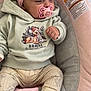 baby, infant, pacifier, headband, flower, clothing, bambi, hoodie, pants, socks, baby_seat, cushion, pink, gray, cute, portrait, indoors, child, small_fist, relaxed