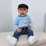Kézyo a rejoint le concours — aidez-le/la à gagner de superbes lots ! toddler, child, boy, cap, blue_shirt, jeans, white_sneakers, gold_chain, sitting, indoor, portrait, cute, fashion, expression, casual, young, person, footwear, hat, smiling