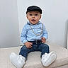 toddler, child, boy, cap, blue_shirt, jeans, white_sneakers, gold_chain, sitting, indoor, portrait, cute, fashion, expression, casual, young, person, footwear, hat, smiling