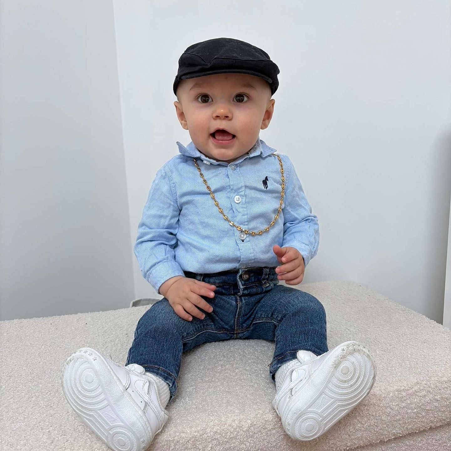 Kézyo a rejoint le concours — aidez-le/la à gagner de superbes lots ! toddler, child, boy, cap, blue_shirt, jeans, white_sneakers, gold_chain, sitting, indoor, portrait, cute, fashion, expression, casual, young, person, footwear, hat, smiling