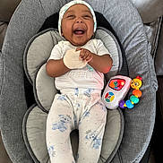 Zaire joined the competition — help win amazing prizes! baby, infant, child, smiling, laughing, portrait, sitting, baby_seat, cushion, hat, onesie, clothing, toy, rattle, caterpillar_toy, colorful, indoors, happy, playful, photography