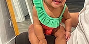Meilani is registered to the contest to win money with this photo: toddler, child, smiling, indoor, mirror, green_clothing, orange_clothing, white_shoes, sitting, person, flooring, door, reflection, hair_tie, cute, happy, baby, hand, face, portrait