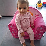 Victoria a rejoint le concours — aidez-le/la à gagner de superbes lots ! toddler, child, pink_chair, pajamas, indoor, toys, floor, curious, sitting, barefoot, home, relaxed, young_child, furniture, person, casual_clothing, portrait, cute, baby, playroom