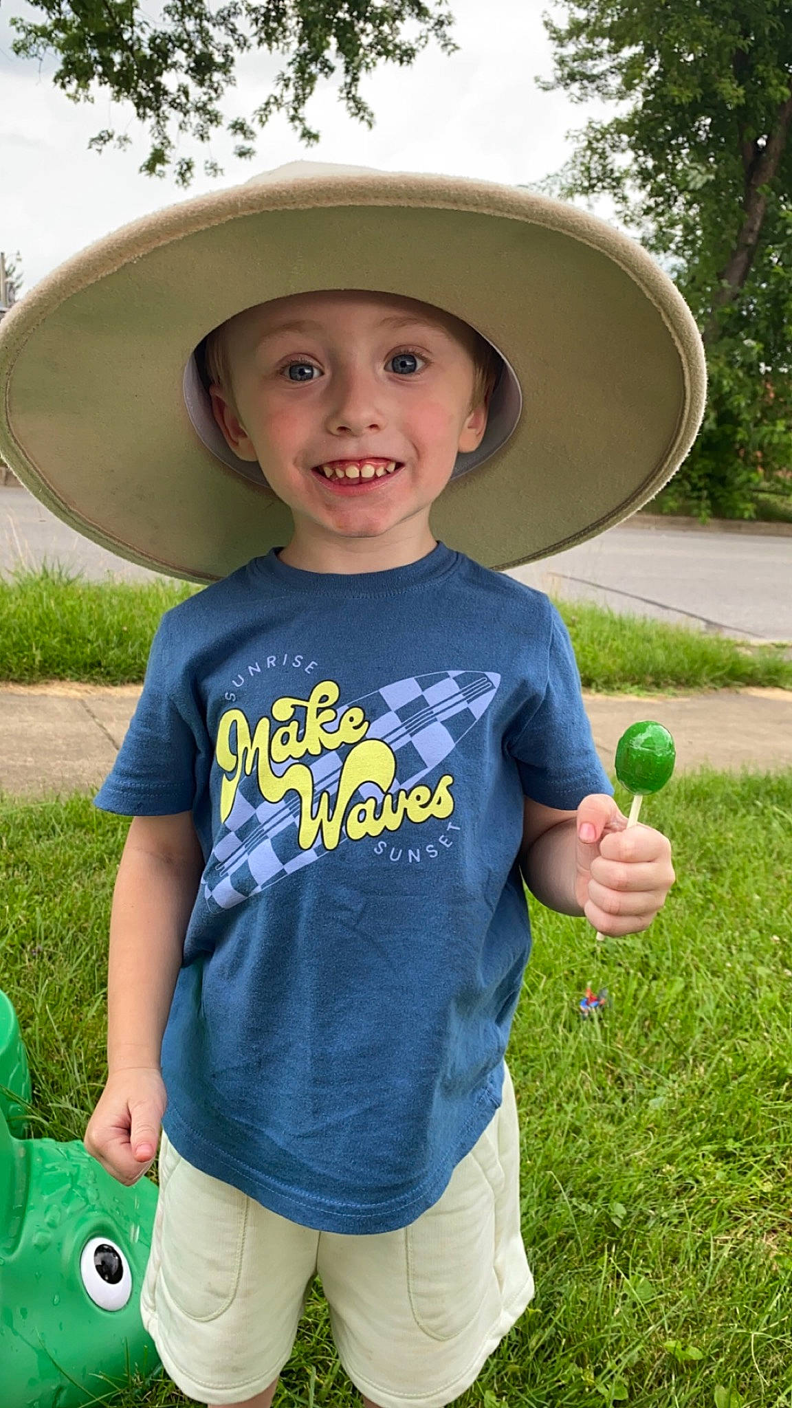 Ezra is registered to the contest to win money with this photo: baby_toddler_clothing, cap, cool, face, facial_expression, fun, grass, green, happy, hat, headgear, headwear, joy, leisure, people_in_nature, person, plant, public_space, sleeve, smile