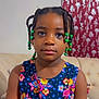 child, girl, braids, beads, dress, floral_pattern, couch, indoor, portrait, face, calm, seated, furniture, curtain, pattern, colorful, person, young, hairstyle, casual
