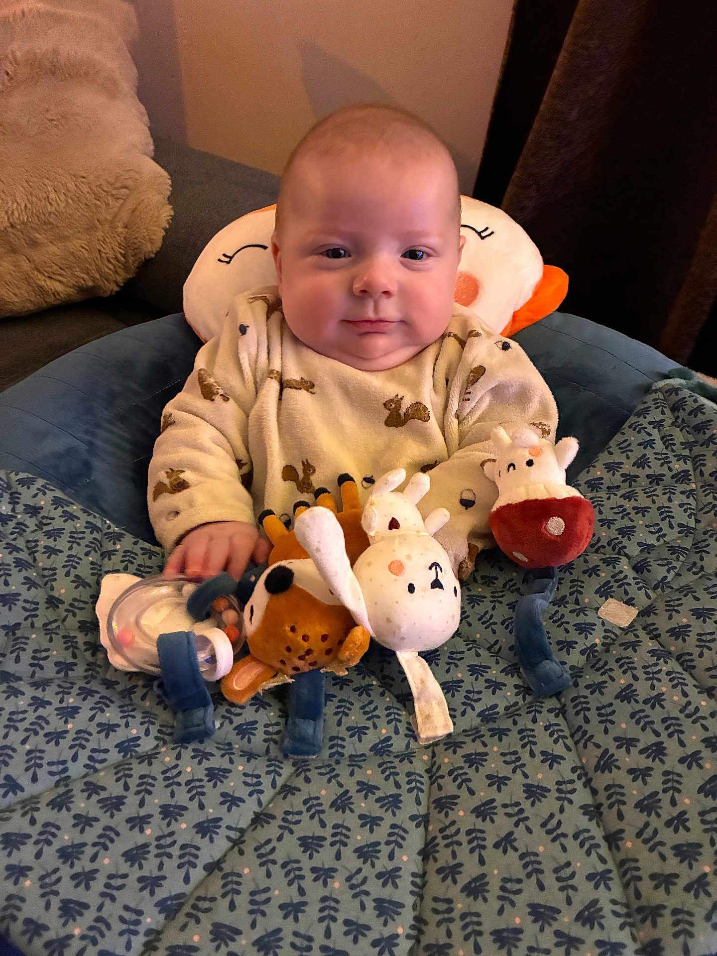 Lysio participe au concours pour gagner de l'argent avec cette photo : baby, infant, plush_toy, stuffed_animal, blanket, pillow, sitting, indoors, child, clothing, cute, face, person, soft_toy, comfort, patterned_blanket, head_support, happy, smile, cozy