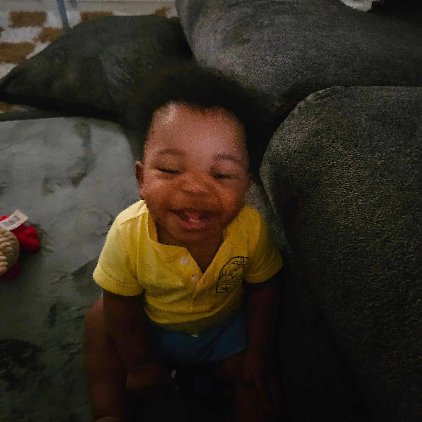 Micah joined the competition — help win amazing prizes! toddler, child, smiling, yellow_shirt, carpet, couch, indoor, happy, sitting, blurred, joyful, young_child, living_room, furniture, person, home, cozy, candid, afro_hair, playful