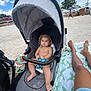 baby, stroller, beach, sand, hat, towel, legs, person, child, running, car, fence, bird, seagull, sky, clouds, sun, outdoor, summer, relaxation