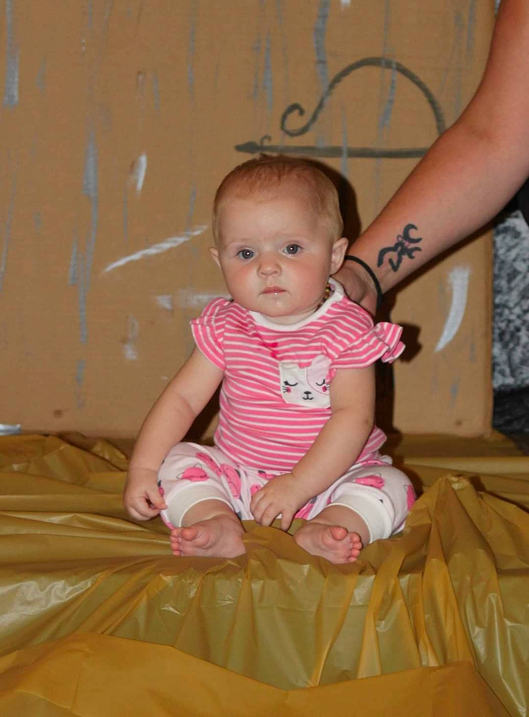 Kimber is registered to the contest to win money with this photo: baby, baby_toddler_clothing, barefoot, cheek, child, comfort, eye, face, finger, floor, flooring, fun, happy, leg, pattern, person, pink, skin, sleeve, toddler