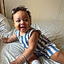 Zoe joined the competition — help win amazing prizes! baby, bed, bracelet, child, curly_hair, cute, face, foot, hair_bow, hand, happy, indoor, infant, person, portrait, sitting, skin, smiling, striped_outfit, white_sock