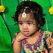 Sitara joined the competition — help win amazing prizes! toddler, child, portrait, traditional_clothing, jewelry, green_background, yellow_flowers, curly_hair, cute, decorative, face, expression, indoor, closeup, costume, person, head, hand, colorful, young