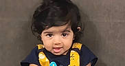 Sitara is registered to the contest to win money with this photo: baby, broccoli, casual, child, curly_hair, cute, expression, eyes, face, food, hands, holding, indoor, person, playful, portrait, sitting, toddler, yellow_clothing, young_child