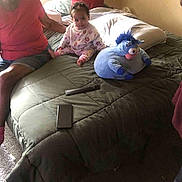 Anice joined the competition — help win amazing prizes! toddler, bed, adult, plush_toy, remote_control, smartphone, window, blanket, pillow, carpet, indoor, person, furniture, clothing, sitting, child, toy, light, room, home