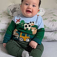 Théo participe au concours pour gagner de l'argent avec cette photo : baby, child, smiling, sitting, sweater, clothing, face, pillow, bed, indoors, cute, happy, person, portrait, green_pants, gray_socks, hair, toy_motif, fabric, cozy