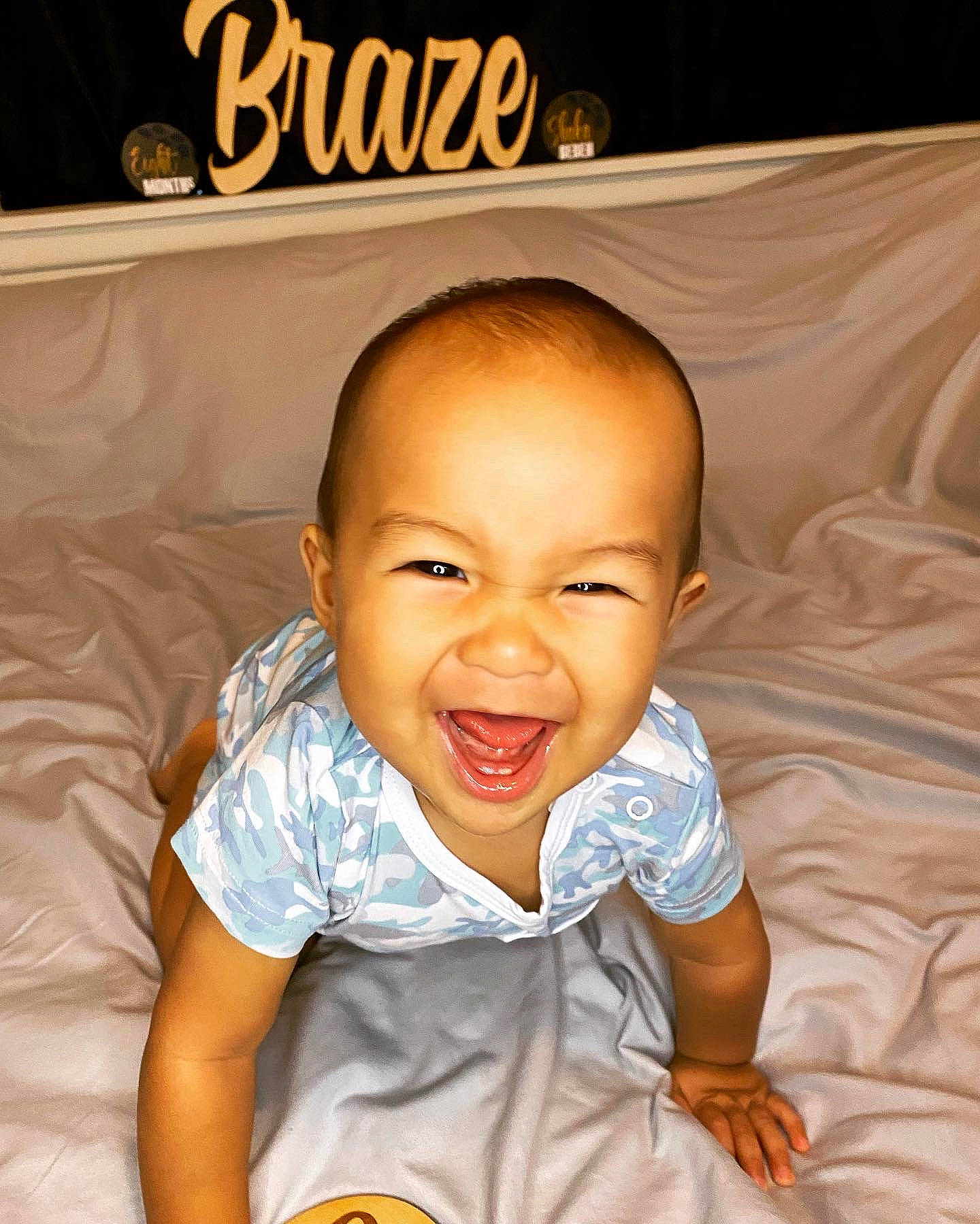 Braze is registered to the contest to win money with this photo: baby, baby_toddler_clothing, cheek, comfort, eye, flash_photography, flooring, fun, gesture, happy, head, mouth, nose, orange, person, skin, sleeve, smile, t_shirt, thumb