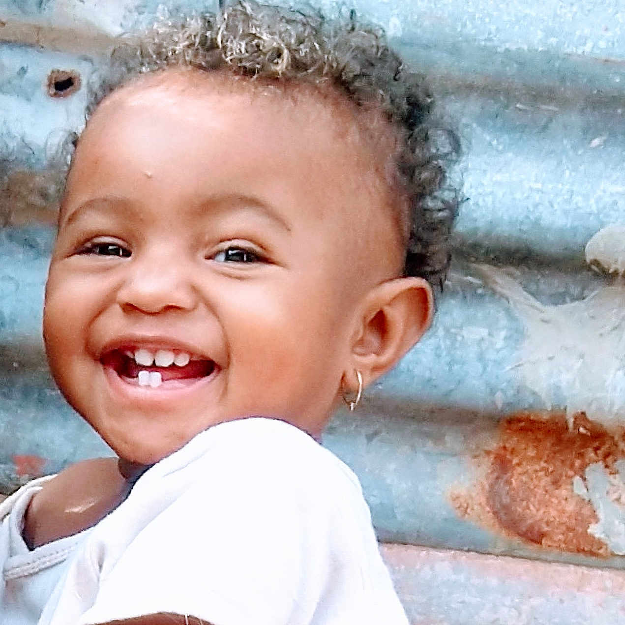 Maïssane participe au concours pour gagner de l'argent avec cette photo : candid, child, closeup, curly_hair, cute, earring, expression, face, happy, joy, metal, outdoor, person, portrait, rusty_background, skin, smiling, teeth, toddler, white_shirt