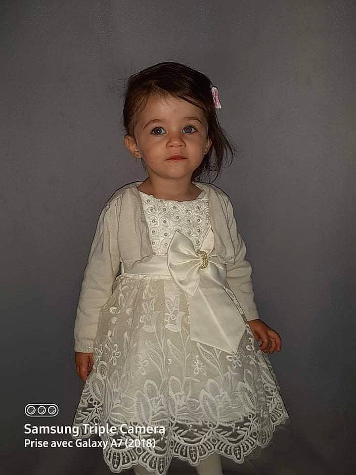 Shaïna a rejoint le concours — aidez-le/la à gagner de superbes lots ! baby_toddler_clothing, bridal_accessory, child, day_dress, dress, embellishment, fashion_accessory, fashion_design, flash_photography, formal_wear, happy, neck, one_piece_garment, pattern, person, pink, ruffle, skin, sleeve, toddler
