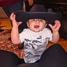 Kayden joined the competition — help win amazing prizes! toddler, child, cowboy_hat, hat, smiling, indoor, person, carpet, floor, shirt, puma, camouflage, hand, face, legs, jeans, living_room, adult, furniture, television