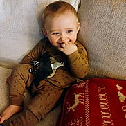 Jace Tyler Wylie is registered to the contest to win money with this photo: toddler, child, smiling, pajamas, plush_toy, bat_toy, couch, cushion, holiday, christmas, red_pillow, beige_couch, indoor, cozy, happy, face, person, sitting, fingers_in_mouth, cute