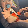 Fin is registered to the contest to win money with this photo: baby, pacifier, car_seat, child, reaching_hand, safety_harness, car_interior, sunlight, infant, cute, seat_belt, window, portrait, young_child, child_safety, car, seat, smiling, person, daylight