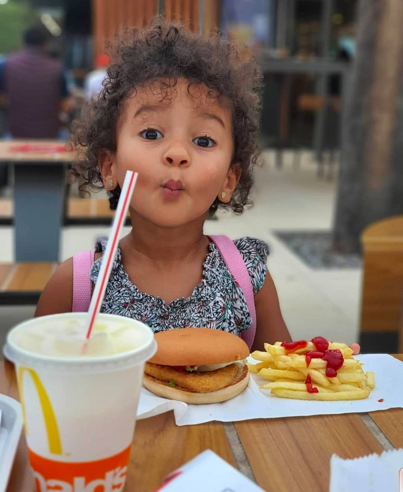 Rihanna is registered to the contest to win money with this photo: chair, child, cuisine, cup, dish, drink, drinking_straw, drinkware, fast_food, food, food_craving, french_fries, fun, person, photograph, plate, snapshot, surprise, sweetness, table