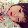 Lily is registered to the contest to win money with this photo: baby, child, face, close_up, floral, cushion, pink, pattern, sleepwear, hand, indoors, cute, portrait, infant, young, expression, resting, soft, skin, hair