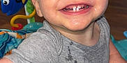 Oaklee joined the competition — help win amazing prizes! baby, smiling, teeth, face, hand, play_seat, toy, fish_toy, clothing, gray_shirt, indoor, happy, child, infant, person, mouth, expression, blue, orange, green