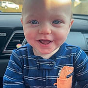 Oaklee joined the competition — help win amazing prizes! baby, child, smiling, face, blue_onesie, dinosaur_patch, car_interior, car_seat, infant, happy, cute, portrait, closeup, young_child, cheerful, indoors, clothing, person, head, eyes