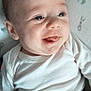 baby, infant, smile, tongue, white_clothing, blanket, face, expression, cute, happy, child, person, indoors, portrait, newborn, lying_down, closeup, soft_light, cozy, young