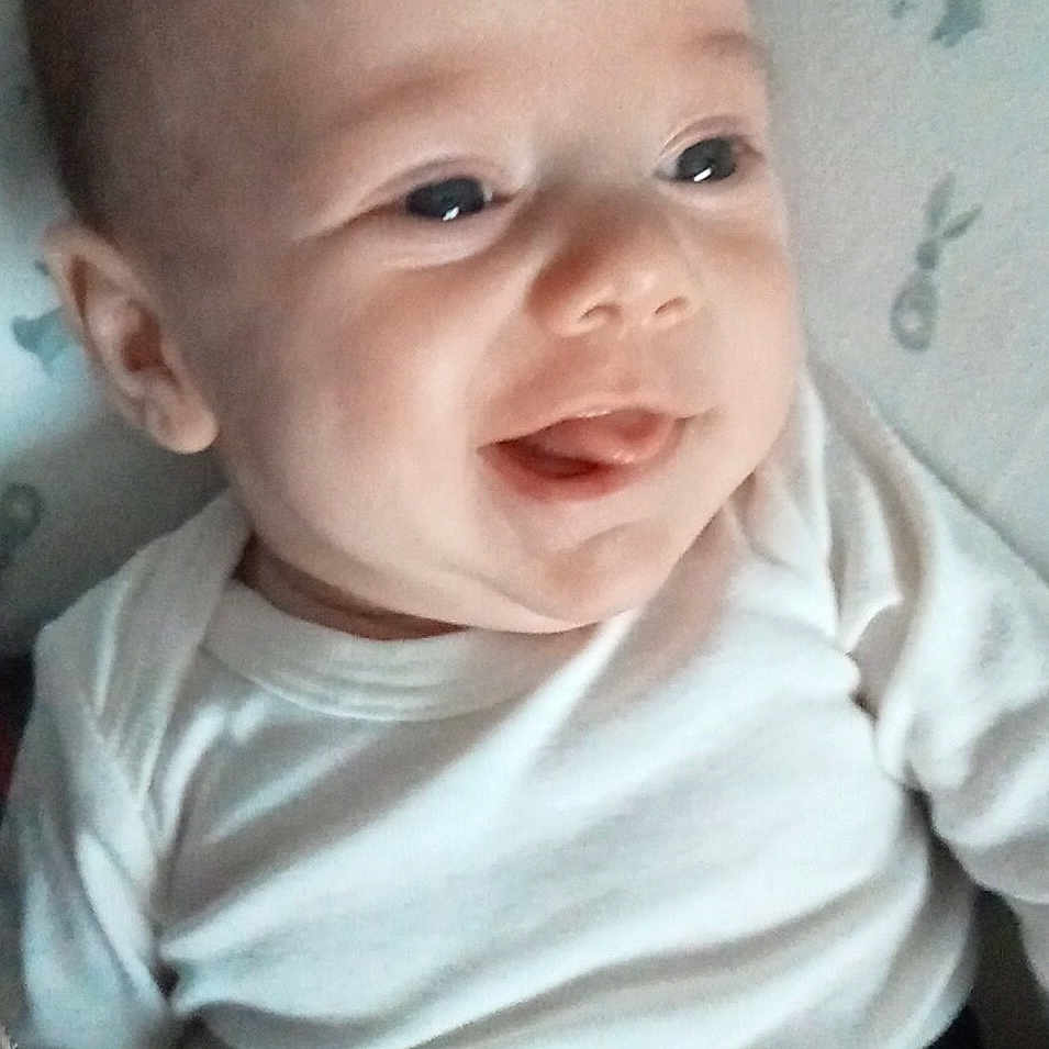 Loric participe au concours pour gagner de l'argent avec cette photo : baby, blanket, child, closeup, cozy, cute, expression, face, happy, indoors, infant, lying_down, newborn, person, portrait, smile, soft_light, tongue, white_clothing, young