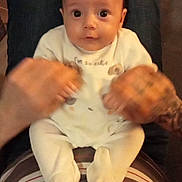 Loric a rejoint le concours — aidez-le/la à gagner de superbes lots ! adult, baby, casual, child, couch, cute, face, hands, holding_hands, indoor, infant, lap, legs, looking_at_camera, pajamas, person, remote_controls, striped_shirt, tattoo, wooden_table