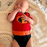 Easton joined the competition — help win amazing prizes! baby, baby_photography, bed, bedding, black_clothing, blanket, cartoon_pattern, child, cozy, hand_in_mouth, indoors, infant, knitted_blanket, lying_down, onesie, orange_clothing, portrait, red_clothing, sleepy, snoopy