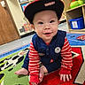 toddler, child, baby, cap, crawling, carpet, playroom, toy, shelf, colorful, smile, face, eyes, floor, clothing, indoor, cute, red, blue, young_child