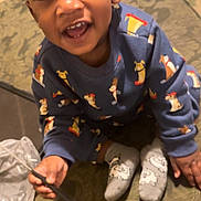 Aiden is registered to the contest to win money with this photo: carpet, child, couch, cute, expression, eyes, face, furniture, hand, happy, indoors, patterned_clothing, person, playful, sitting, smiling, socks, sweatshirt, toddler, toy