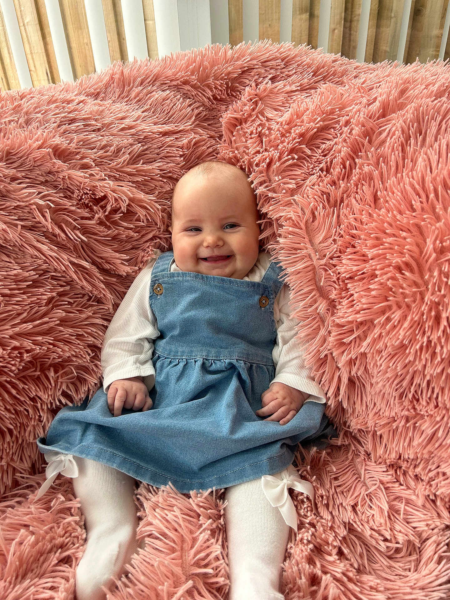 Rosa joined the competition — help win amazing prizes! baby, smiling, denim_dress, white_tights, pink_blanket, fluffy, indoor, cute, child, happy, portrait, sitting, cozy, soft_texture, infant, comfort, clothing, joyful, warm, young