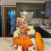 Rosa joined the competition — help win amazing prizes! baby, pumpkin, halloween, costume, kitchen, counter, headband, bow, clothing, infant, face, expression, orange, white, modern, appliances, cabinet, sink, table, person