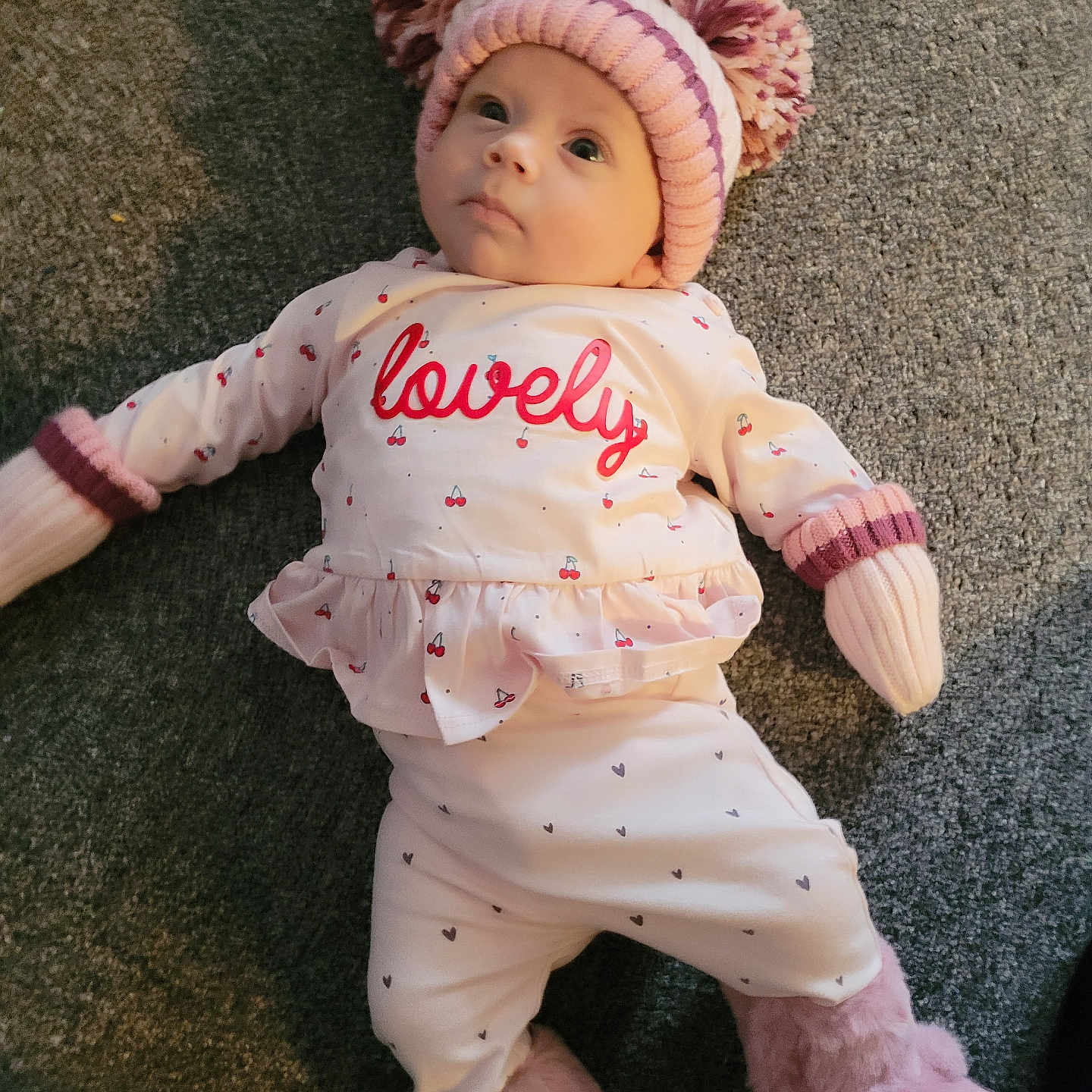 Libby-Rae joined the competition — help win amazing prizes! baby, booties, carpet, child, cozy, cute, face, floor, hat, indoor, infant, looking_up, lying_down, pajamas, person, pink, pom_poms, soft_texture, warm_clothing, white