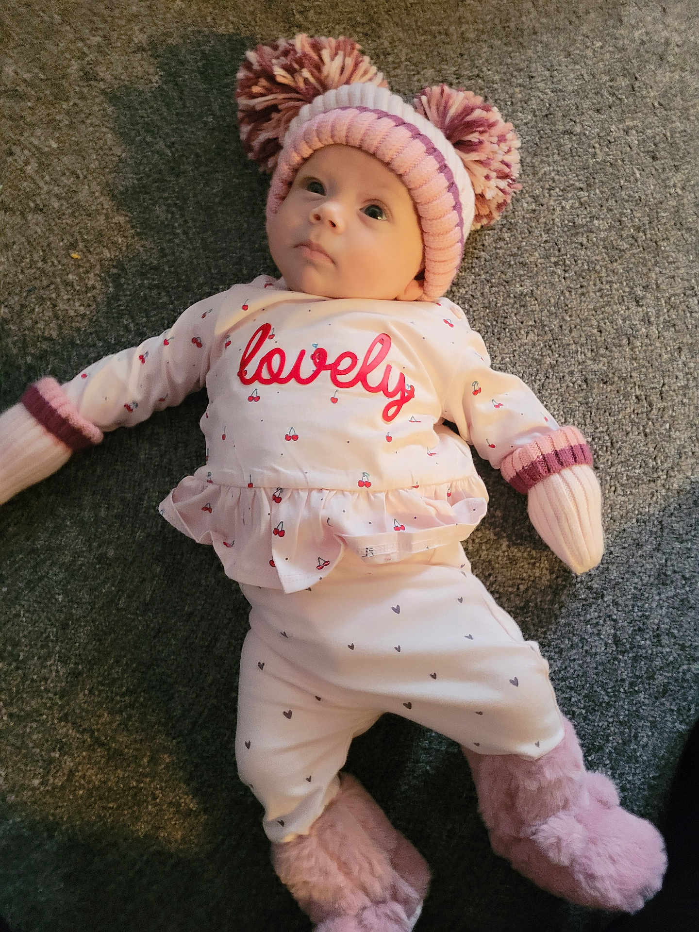 Libby-Rae joined the competition — help win amazing prizes! baby, infant, child, pajamas, hat, pom_poms, carpet, floor, lying_down, pink, white, cozy, warm_clothing, booties, cute, indoor, person, face, looking_up, soft_texture
