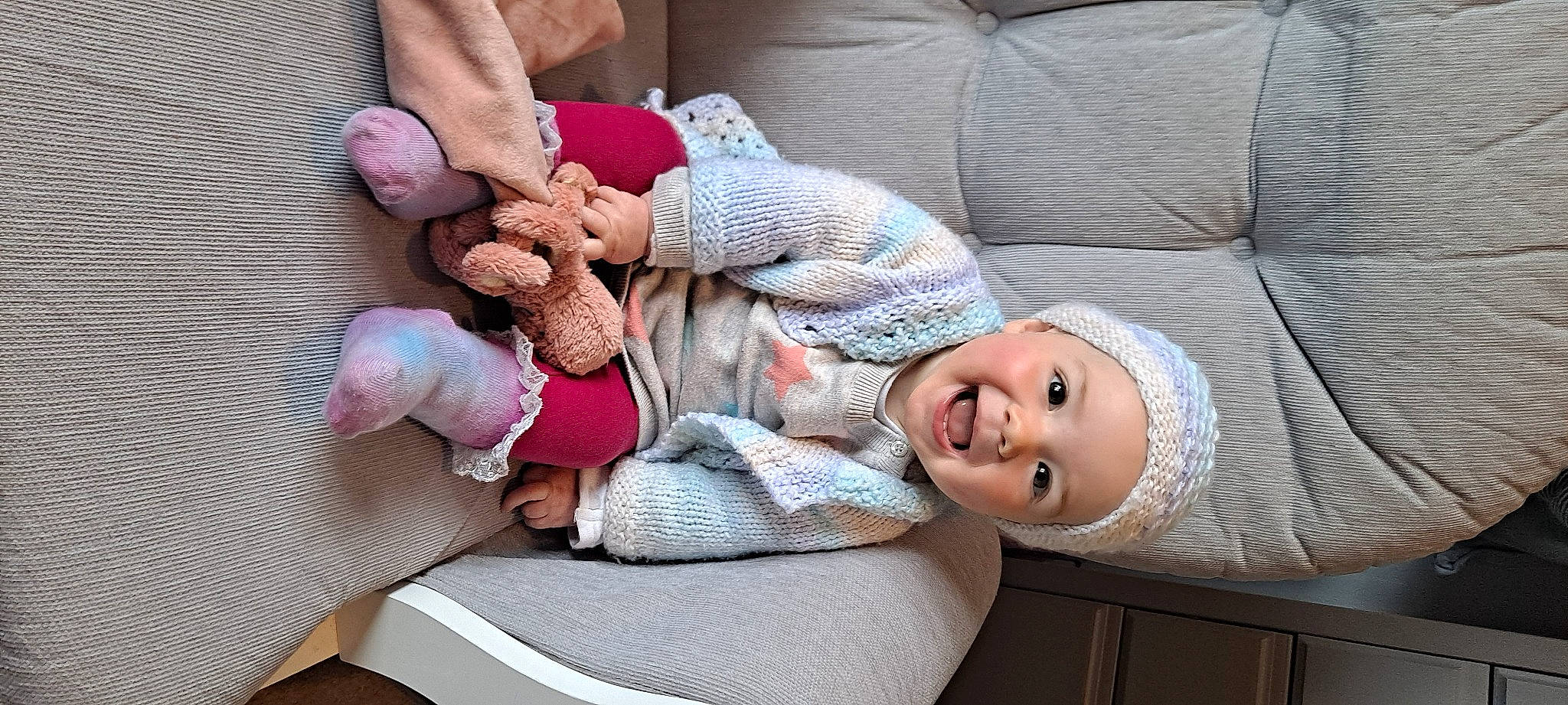 Alma is registered to the contest to win money with this photo: arm, child, comfort, couch, eye, gesture, hand, happy, headwear, joint, lap, leg, mammal, person, product, skin, smile, textile, thigh, toddler