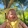 Harper joined the competition — help win amazing prizes! baby, child, yellow_clothing, headband, smiling, outdoor, sunlight, happy, person, face, arm, hand, nature, tree, blurred_background, daylight, infant, cute, portrait, holding