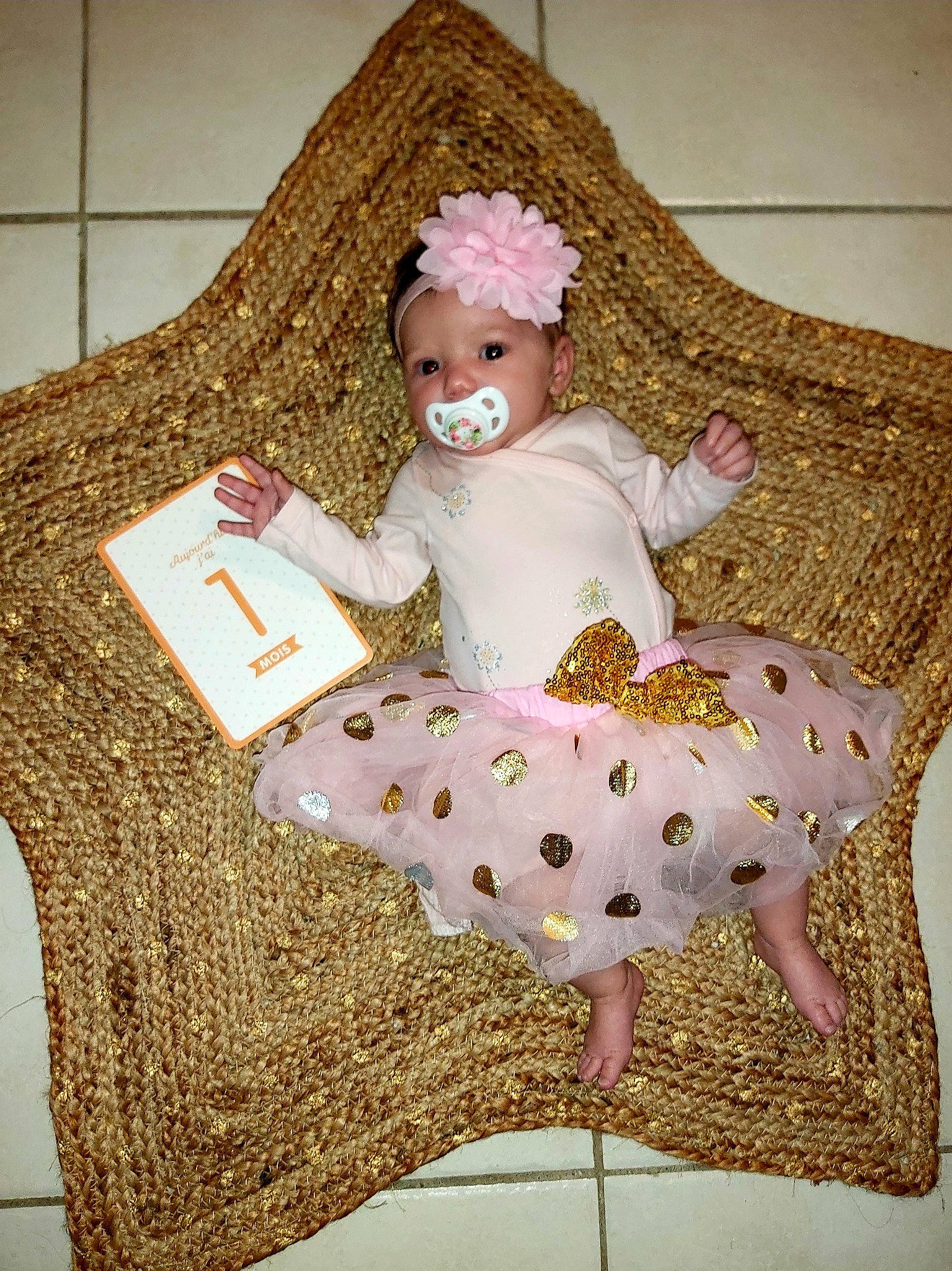 Tya participe au concours pour gagner de l'argent avec cette photo : art, baby, baby_products, baby_toddler_clothing, chair, child, creative_arts, dress, embellishment, fashion_accessory, headband, headpiece, headwear, pattern, peach, person, pink, room, sitting, sleeve