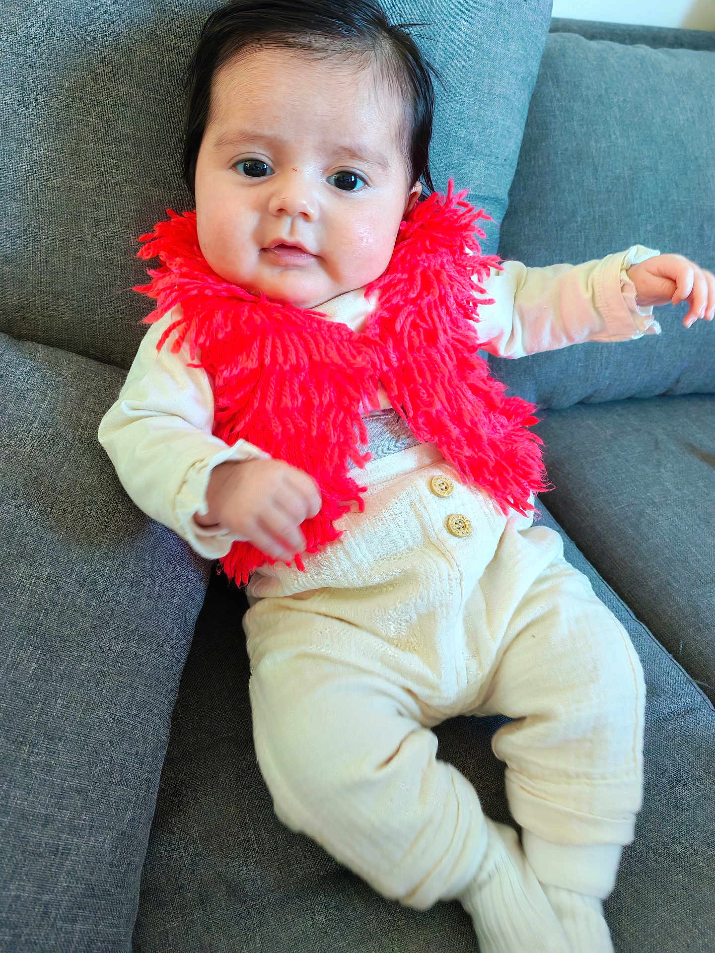 Eva participe au concours pour gagner de l'argent avec cette photo : baby, child, clothing, couch, cream_pants, cute, eyes, face, furniture, hair, hand, indoors, infant, portrait, red_scarf, sitting, smiling, socks, soft_texture, young